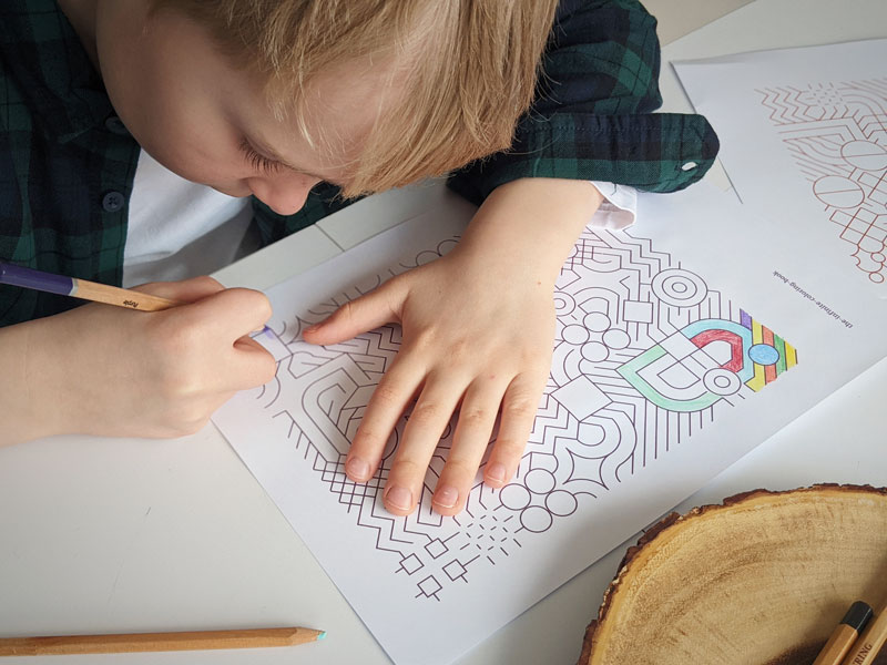 A close up of a child coloring in a pattern from the infinite coloring book